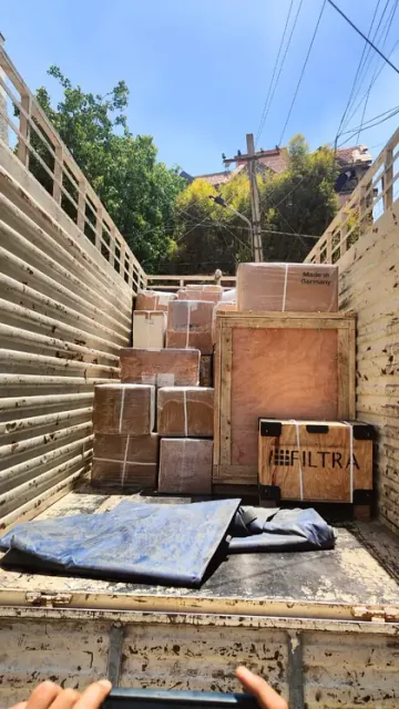Cartons and wooden-framed packages placed in the rear of a cargo vehicle.