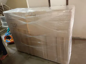 A large furniture piece covered with cardboard and transparent outer film.