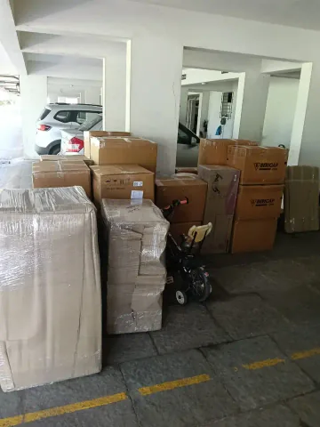 Wrapped household items and sealed cardboard cartons grouped in a building pickup area