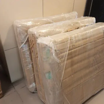 Several flat furniture pieces protected with cardboard and outer wrapping.