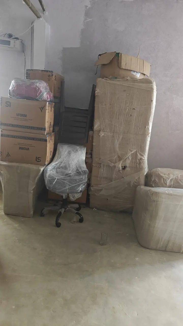 Tall wrapped packages and smaller packed items standing in a storage area.
