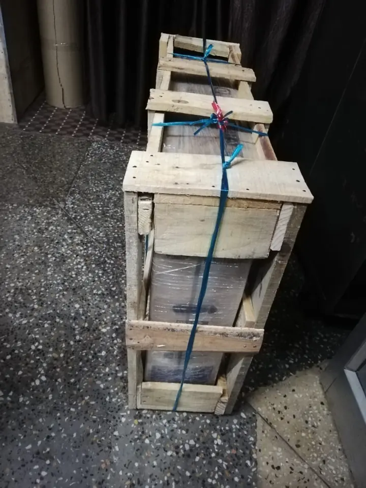 A tall wooden-framed package with straps standing near an entrance.