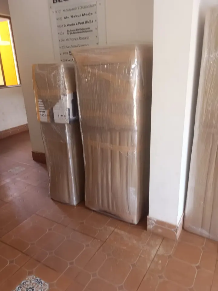 Three differently shaped wrapped household packages standing against an indoor wall.