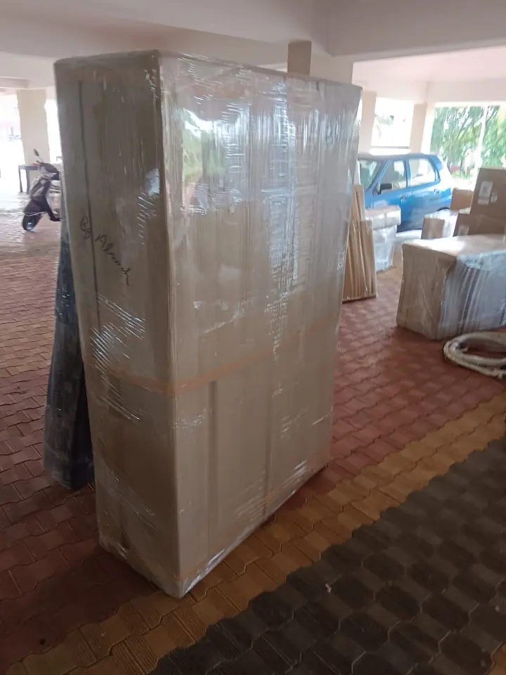 A tall rectangular furniture item covered in clear protective wrap inside a home.