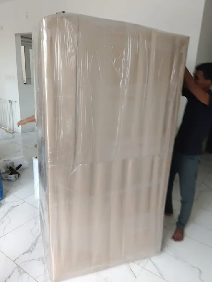 A large mattress standing upright in protective wrapping inside a home.