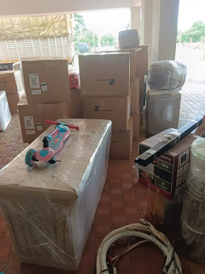 Cartons and wrapped household pieces grouped inside a room, with loose accessories nearby.