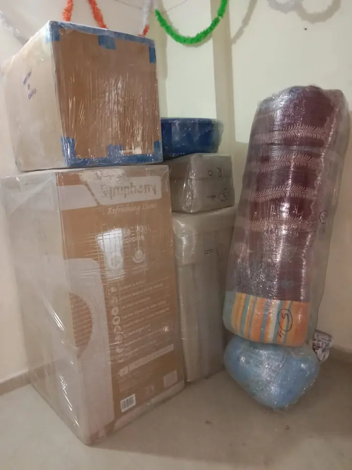 Stacked cartons beside a tall rounded item wrapped in protective material.