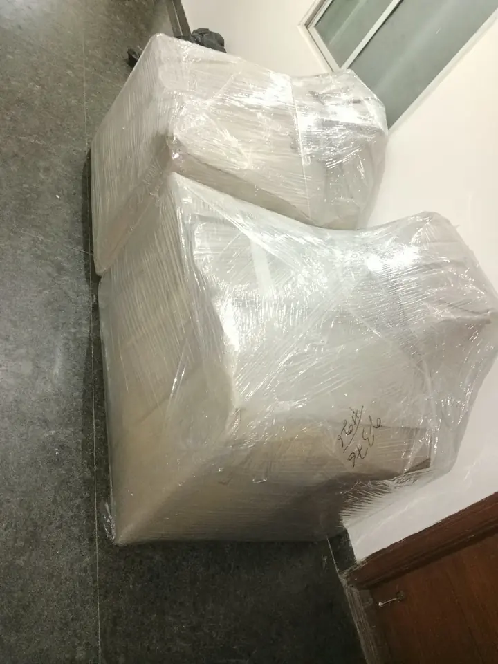 A bulky seat-shaped furniture piece covered with protective wrapping.