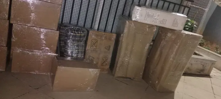 Cartons and tall wrapped household pieces grouped together indoors.