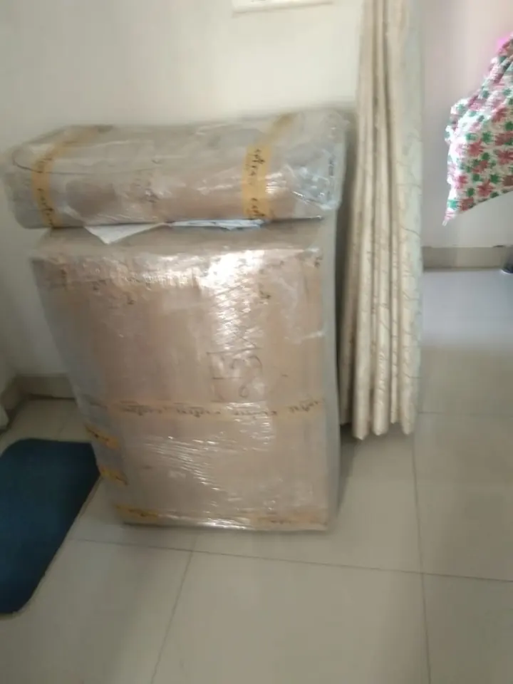 A tall rectangular appliance covered in protective wrapping inside a home.