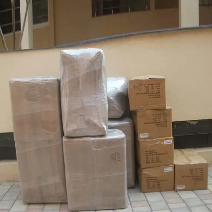 Cartons and upright wrapped household packages grouped along a building corridor.