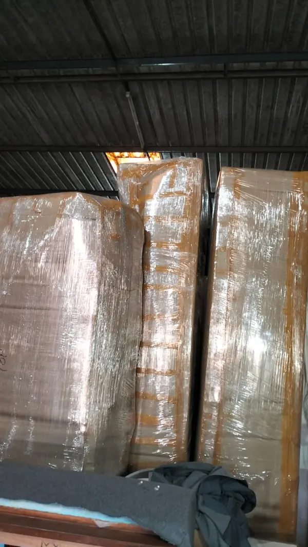 Tall furniture pieces wrapped individually and standing inside a covered storage area.
