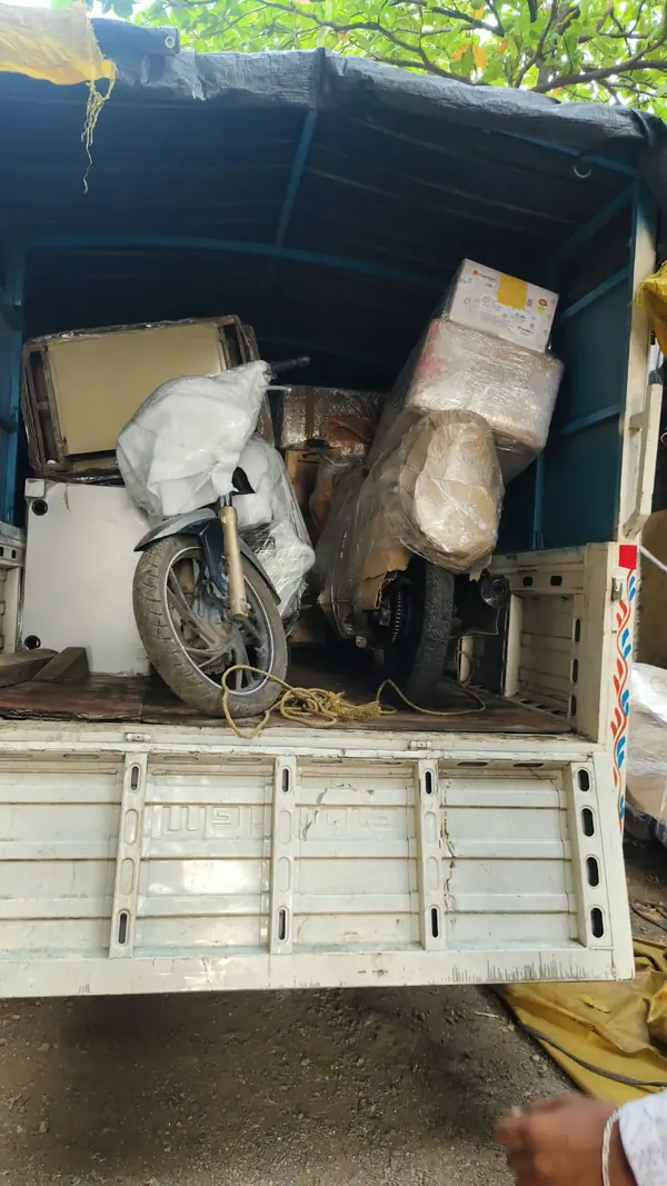 A motorcycle covered in protective material at the rear of a goods vehicle.