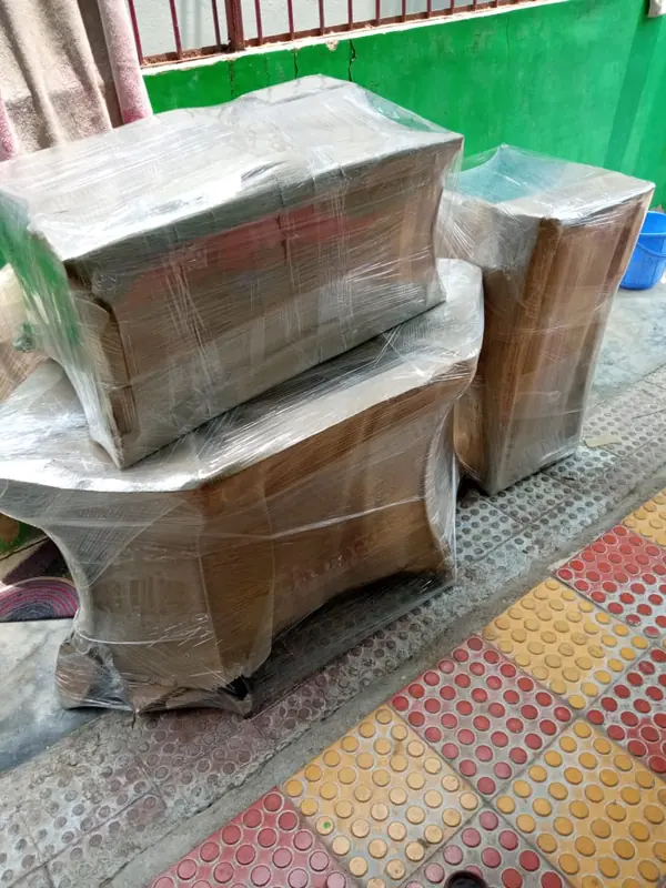 Several rectangular wrapped packages grouped on a patterned floor inside a building.