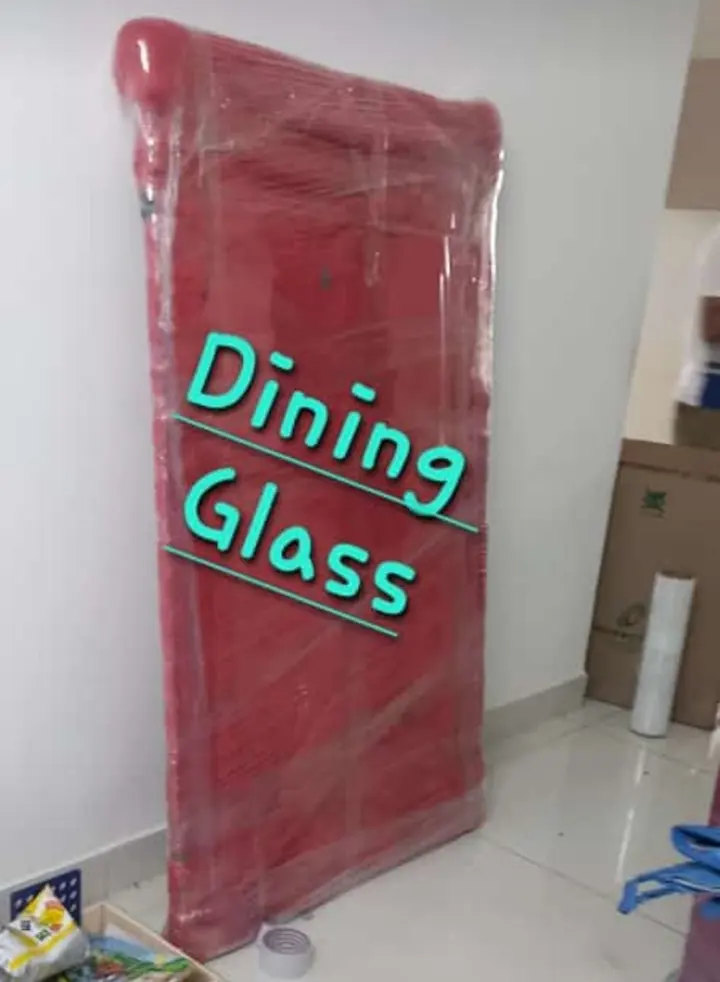 A tall glass dining-table panel covered in red protective material and outer wrapping.