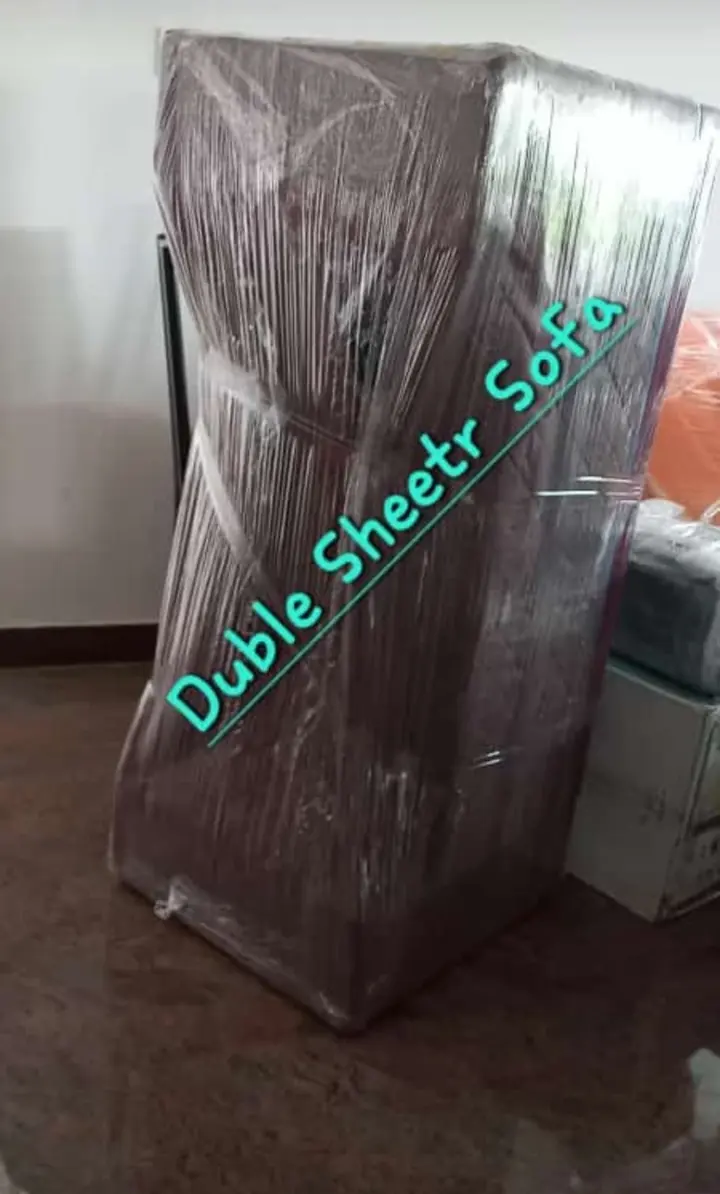 A two-seater sofa standing upright in protective wrapping with an item description on the image.