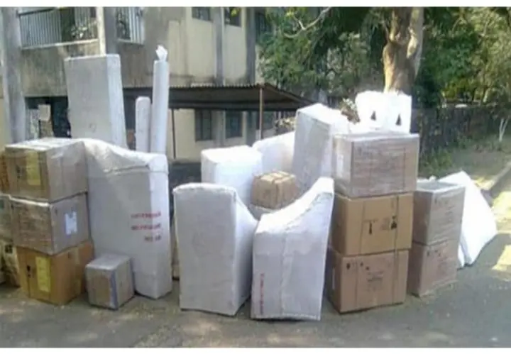 Cartons and differently shaped wrapped household goods grouped outdoors before loading.