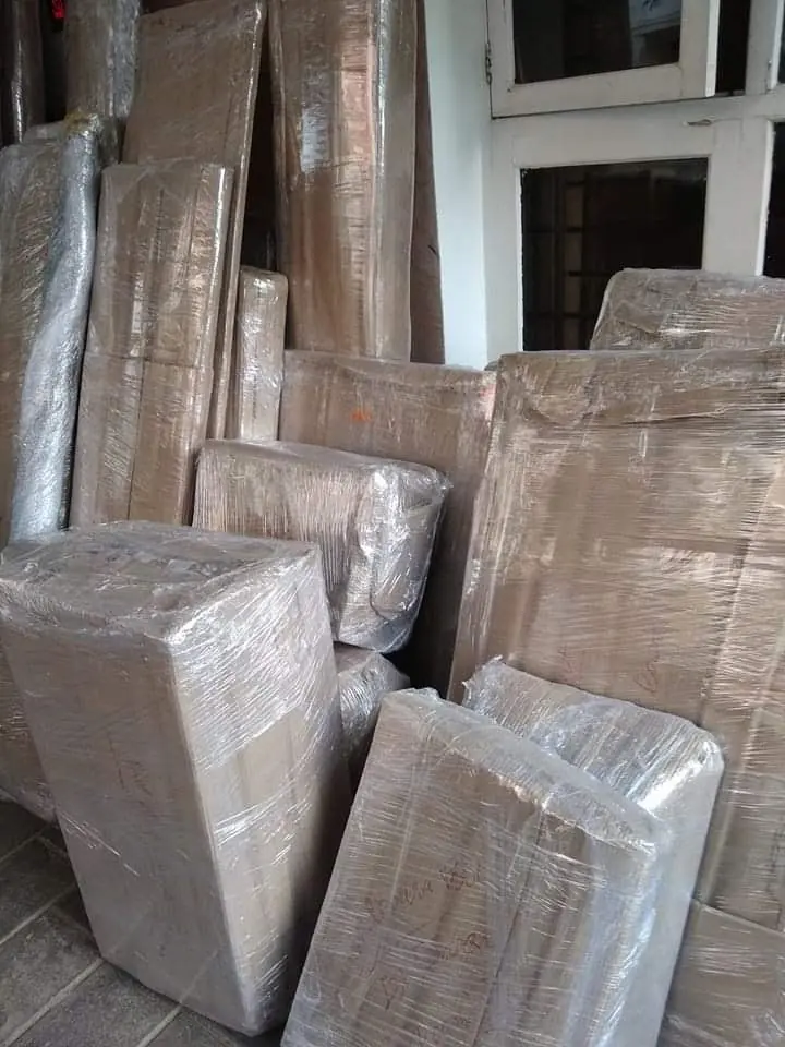 Flat wrapped panels and other furniture packages standing together inside a room.