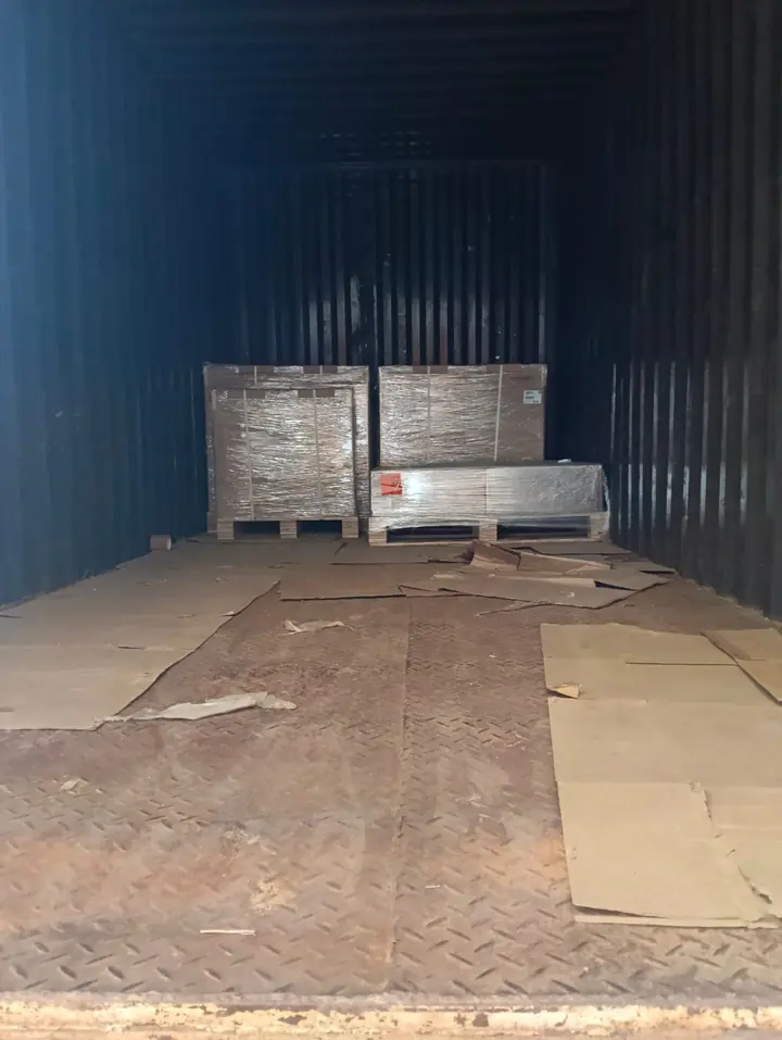 A few wrapped packages positioned at the far end of a mostly empty cargo container.