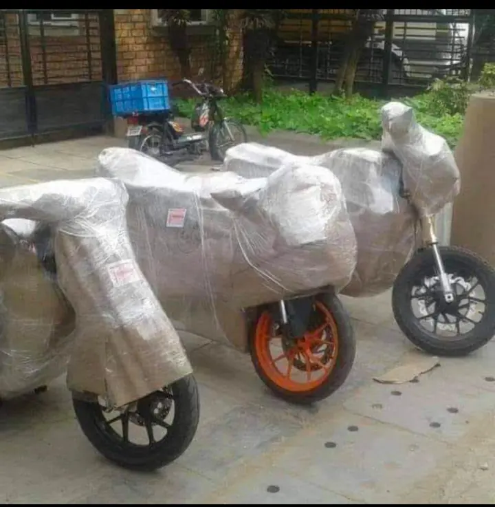 Several motorcycles individually covered in protective wrapping outdoors.