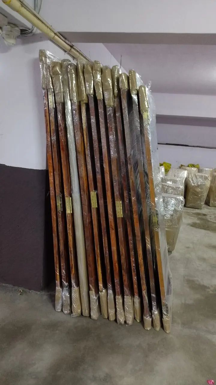 A row of narrow wrapped furniture parts standing together.