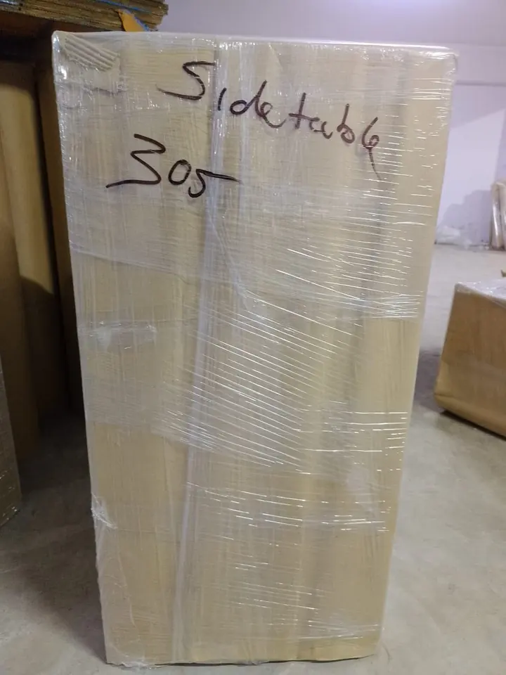 A tall wrapped household package with a handwritten identifying label.
