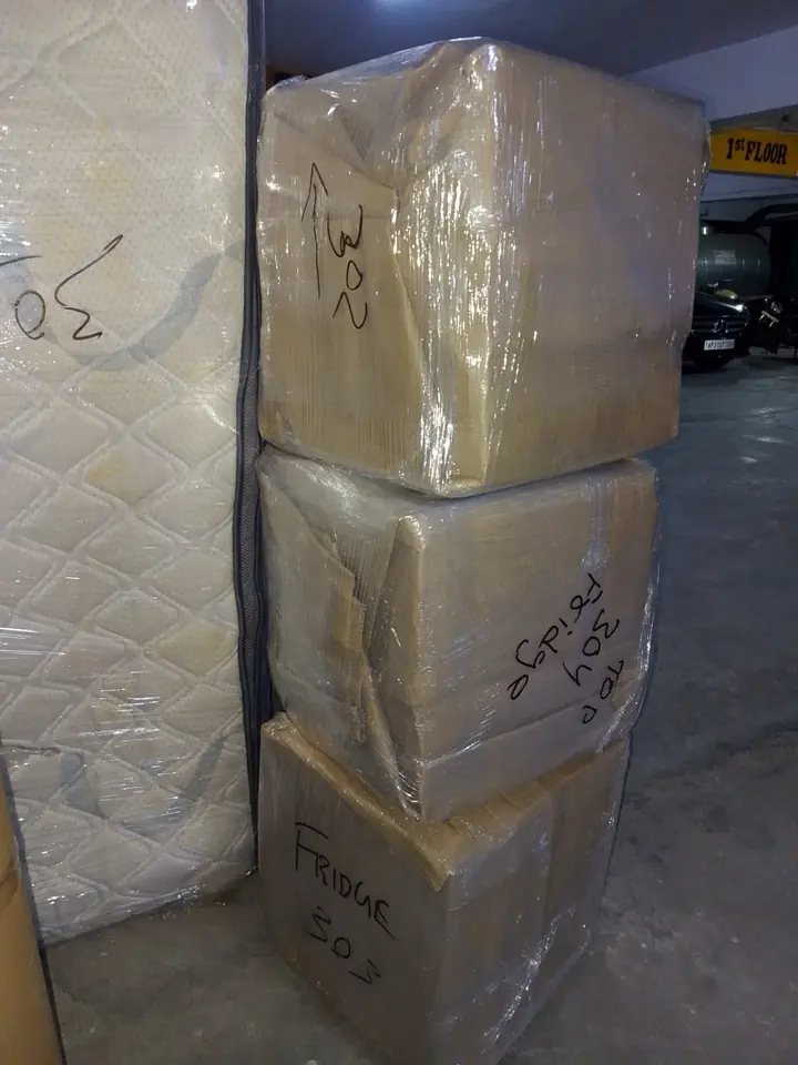 Wrapped household pieces stacked together indoors.