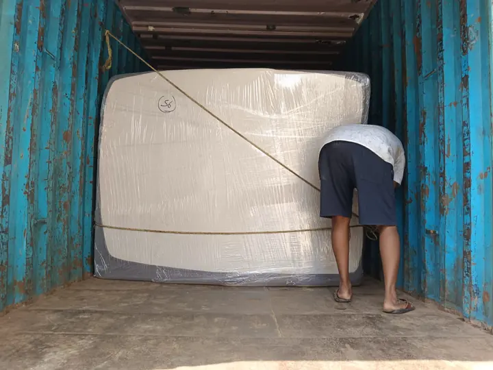 A large wrapped mattress positioned upright inside a cargo vehicle.