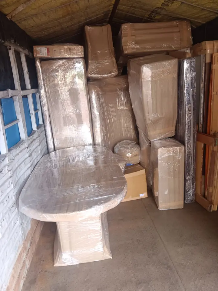 Wrapped tall furniture pieces and a rounded tabletop inside a cargo vehicle.