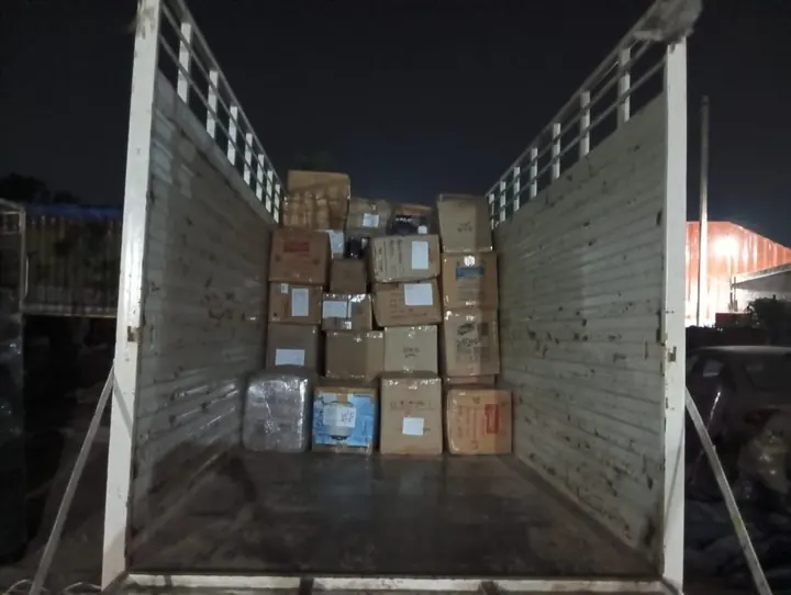 Cartons and wrapped packages arranged inside a truck photographed at night.