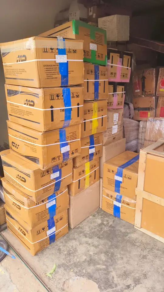 Sealed cardboard cartons with coloured tape and handling labels stacked indoors.