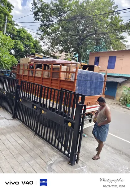 A loaded goods vehicle positioned beside a wide open metal gate.