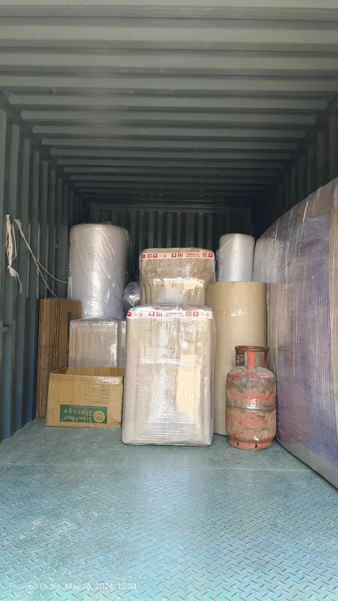 Tall wrapped pieces and smaller packages standing inside an enclosed cargo vehicle.