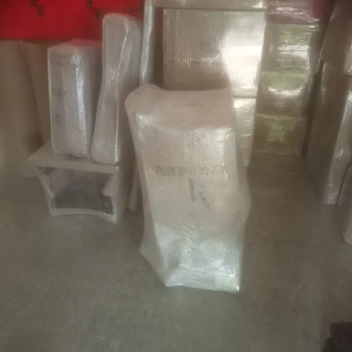Individually wrapped chairs and other upright household packages grouped indoors.