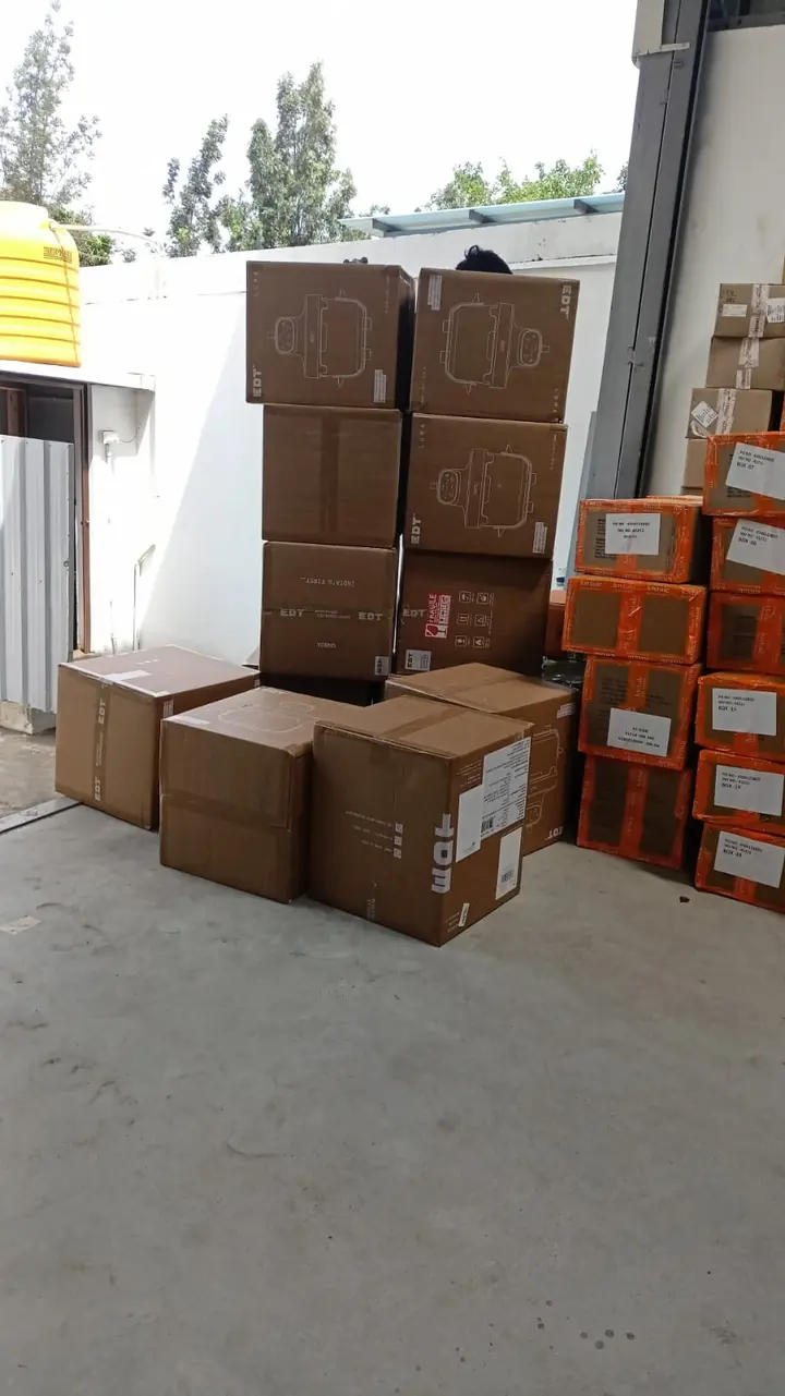 Cartons and larger packed pieces grouped outside a building entrance.