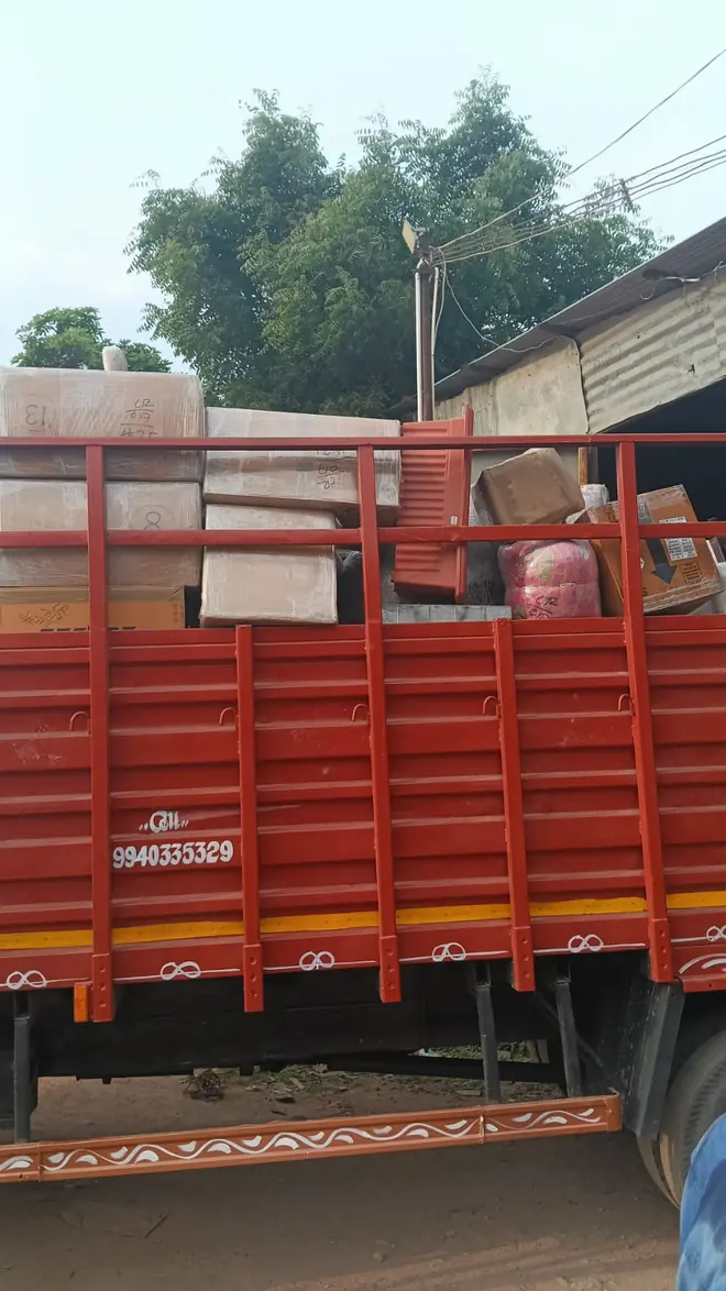 Wrapped household items visible above the side of a red cargo vehicle.