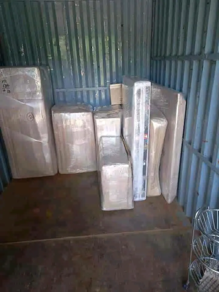 Tall flat furniture pieces wrapped separately and standing inside a cargo container.