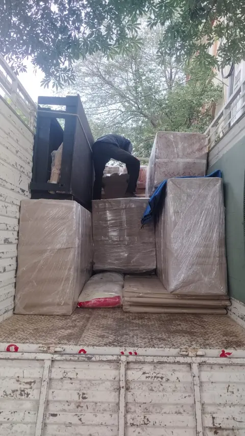 Differently shaped household packages and furniture grouped in the rear of a goods vehicle.