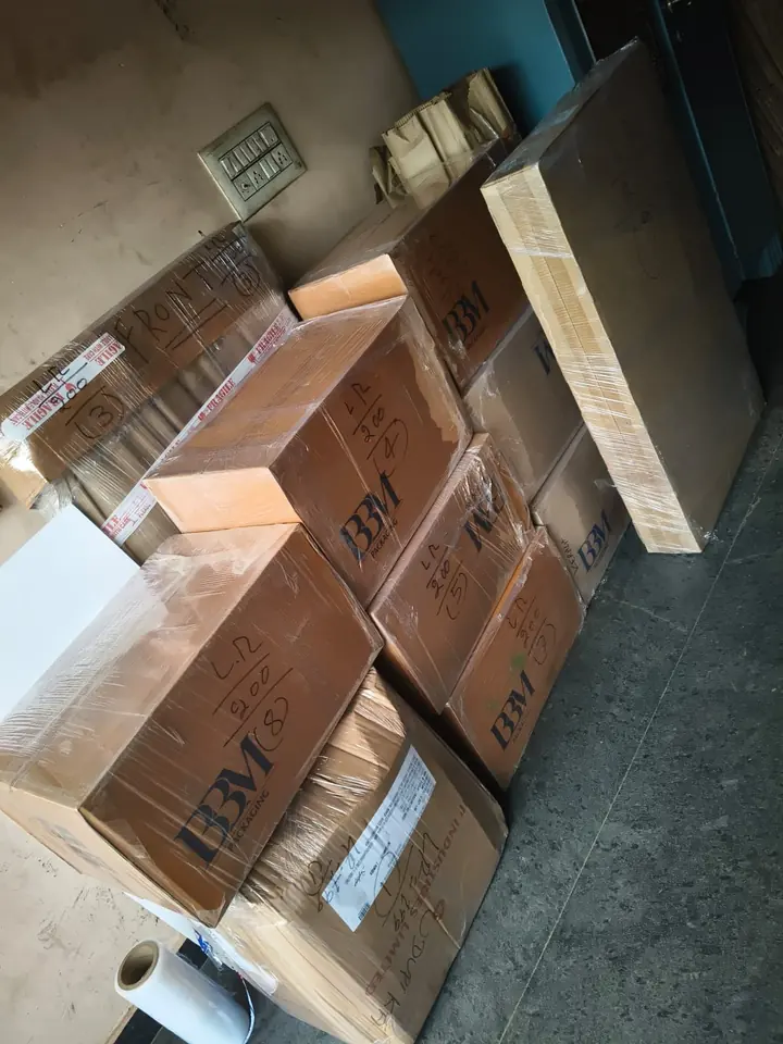 Packed cartons and household pieces grouped together inside a room.