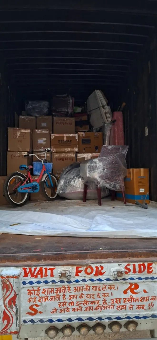 A small bicycle and packed household goods inside an enclosed cargo vehicle.