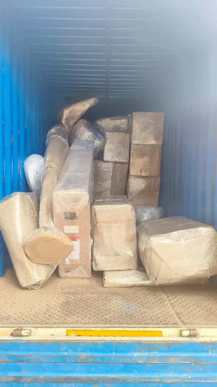 Cartons and several irregular wrapped household packages grouped inside a blue cargo container.
